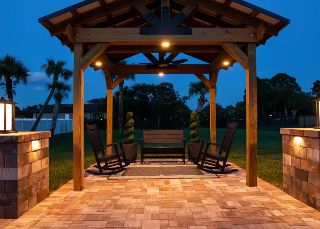Cedar pergola with downlights between lit pillar lanterns on a paver patio at dusk in Melbourne, FL